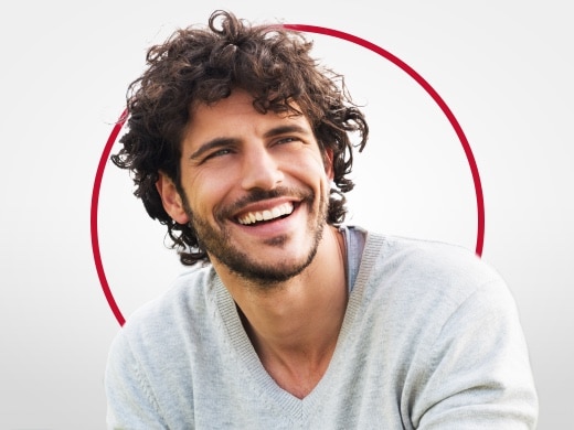 Smilende ung mann i grå genser, glad etter Canesten-behandling mot genital soppinfeksjon