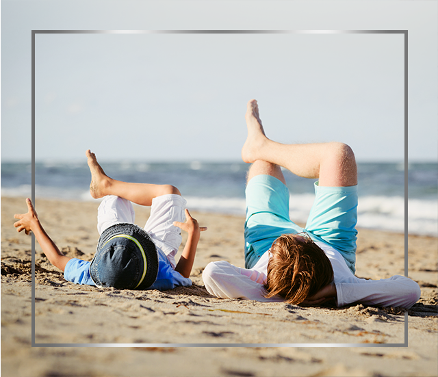 Mor og barn som ligger på stranden med korslagte ben, glade etter Canesten soppbehandling